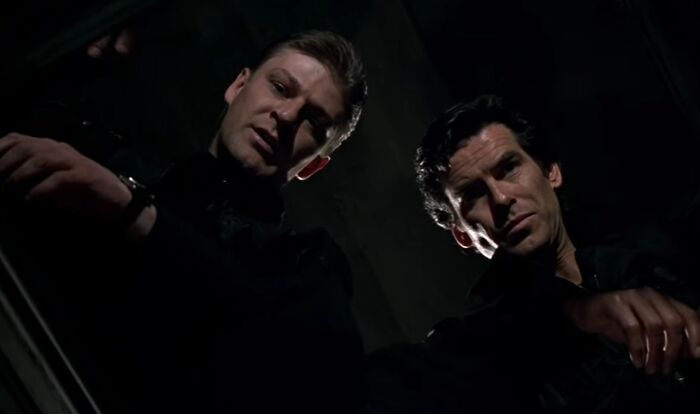 Two men dressed in dark clothing looking down in a dimly lit scene representing actors who became iconic villains.