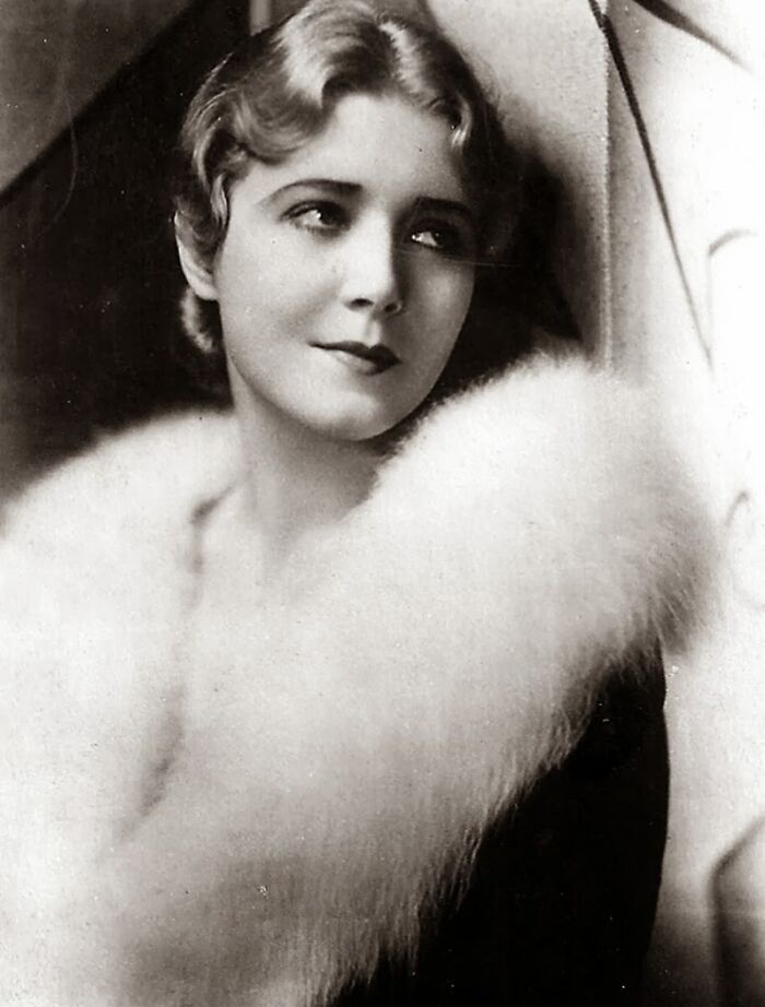 Vintage black and white portrait of a woman with timeless beauty wearing a luxurious fur stole, 1920s style.