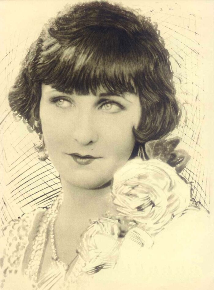 Vintage century-old photo of a woman exemplifying timeless beauty with classic hairstyle and floral accessories.
