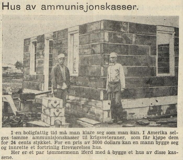 Two men standing next to a small house made of ammunition boxes, an unusual thing found in walls and other places.