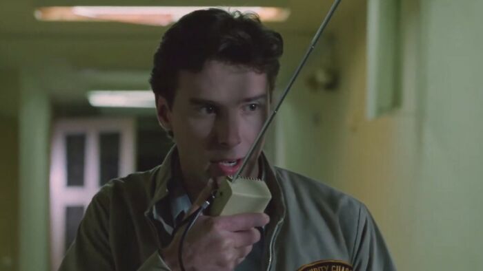 Man in security jacket speaking into a walkie-talkie in a dim hallway, related to worst movies of all time