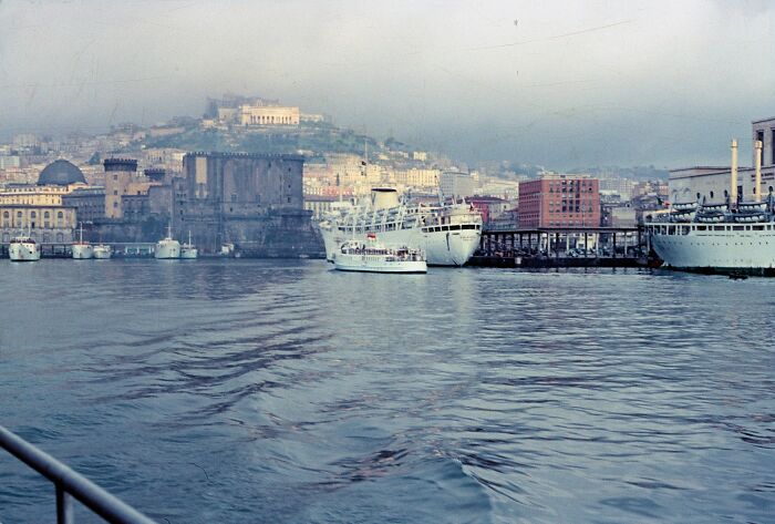 1950s daily life by the harbor with ships docked and a historic cityscape in the background across the globe.