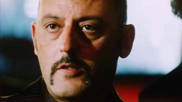 Close-up of a man with a mustache and intense expression in a dark scene representing worst movies of all time.