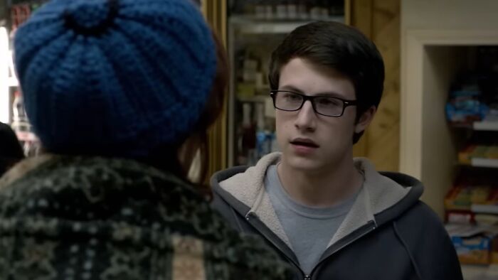 Young man wearing glasses and a hoodie talking inside a store, representing worst movies of all time scenes.