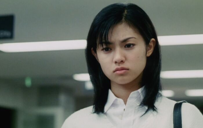Young woman with a serious expression in an indoor setting, representing cinematic crimes in movie sequels.