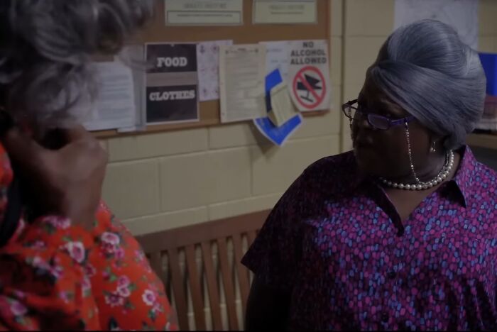 Two women in colorful clothing having a tense conversation in a dimly lit room, depicting cinematic crimes movie sequels.