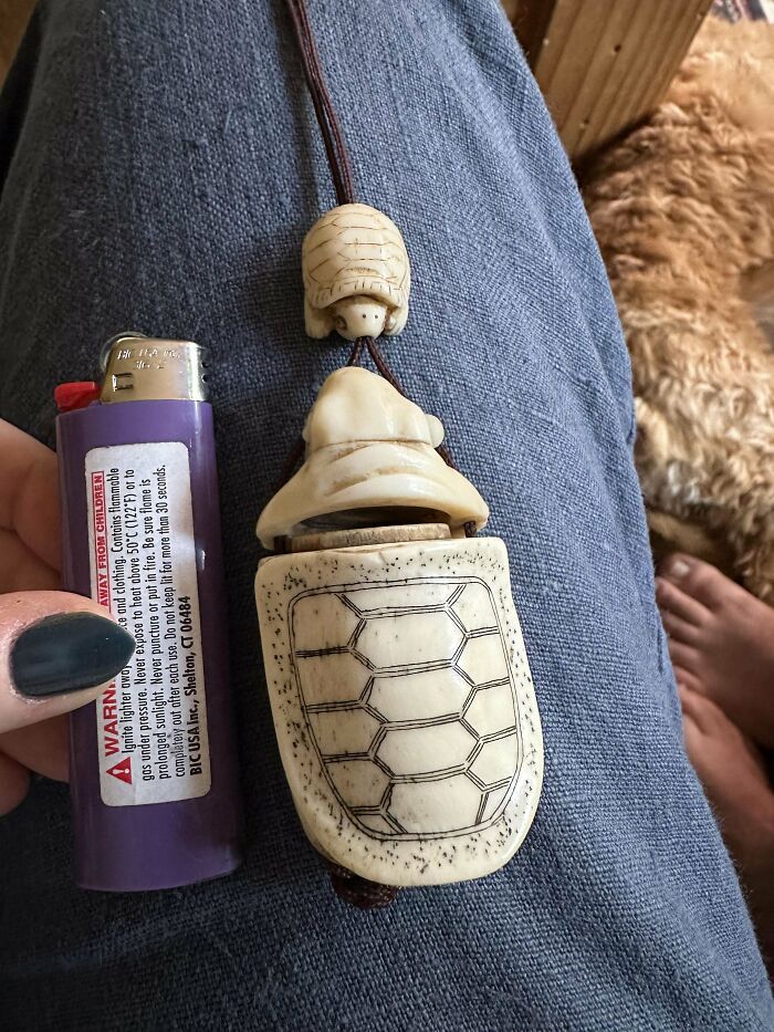 Carved vintage turtle-shaped old collectible item shown next to a lighter for size comparison on denim fabric.