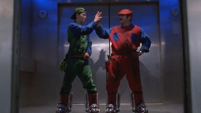 Two men in colorful costumes and rollerblades giving a high five in a dimly lit scene from worst movies of all time.