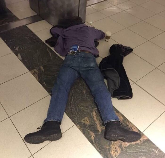 Person lying unbothered on tiled floor with coffee cup nearby, showing zero ducks given about surroundings.