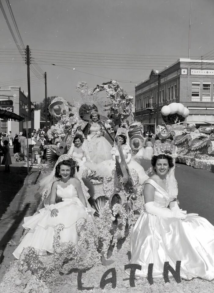 Women in elegant gowns on a decorated parade float, showcasing daily life and celebrations from the 50s.