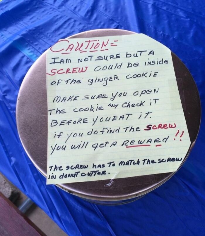 Handwritten caution note about a possible s***w inside a ginger cookie on a round tin, showing suspiciously unbothered attitude.