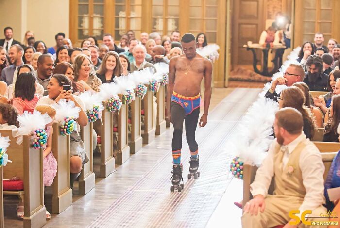 Man in colorful underwear and roller skates walking confidently down an aisle, appearing suspiciously unbothered by audience.
