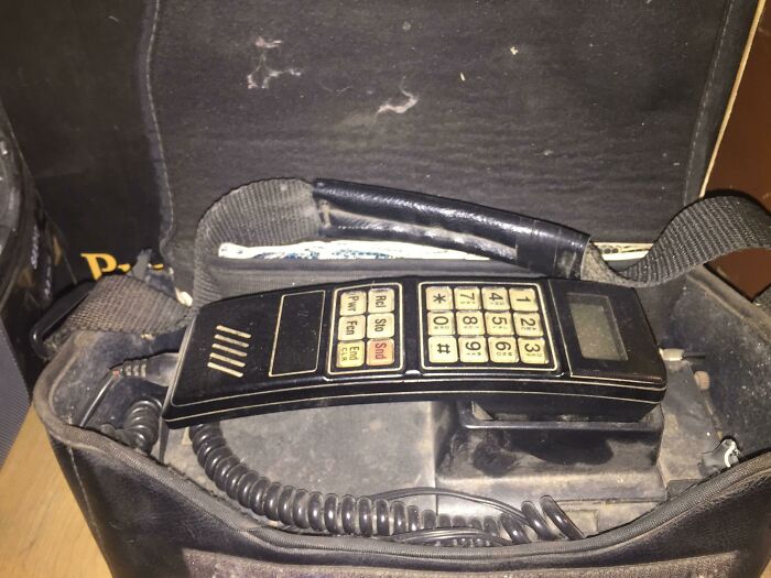 Old landline phone with keypad and coiled cord found inside a bag in an old home discovery.