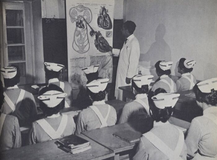 1950s classroom scene with a teacher explaining human anatomy to nurses during daily life across the globe.