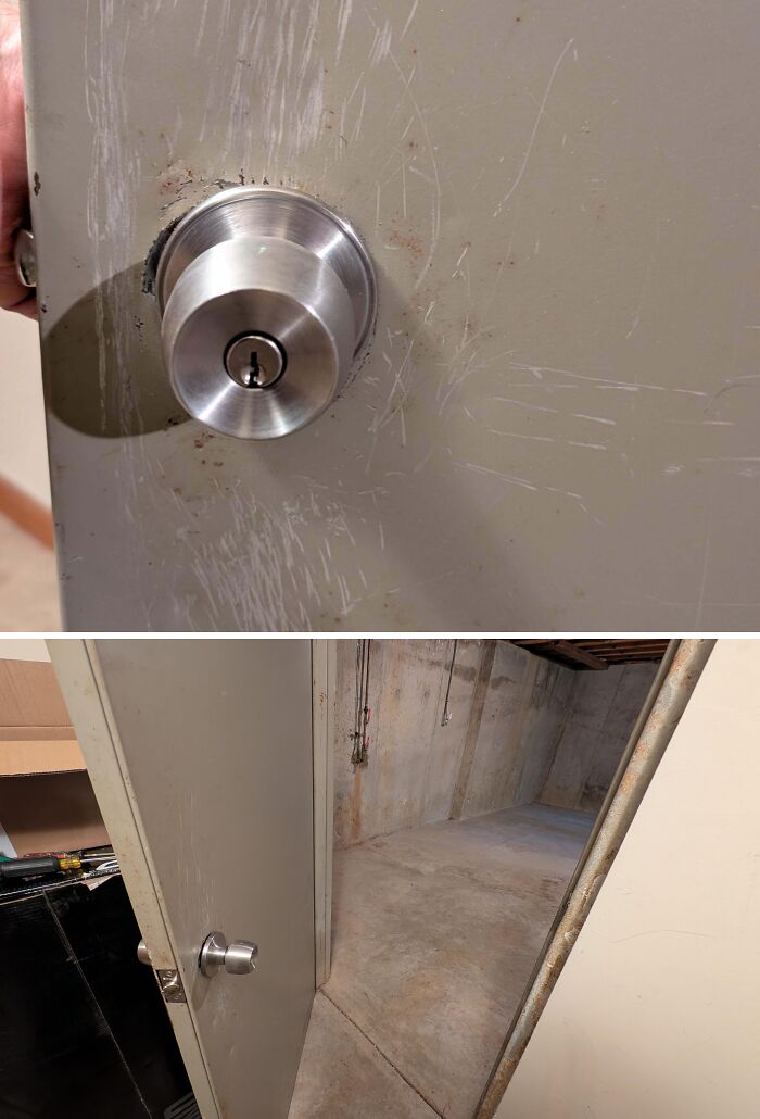 Worn metal door k**b and scratched door opening to an empty concrete basement in an old home discovery.