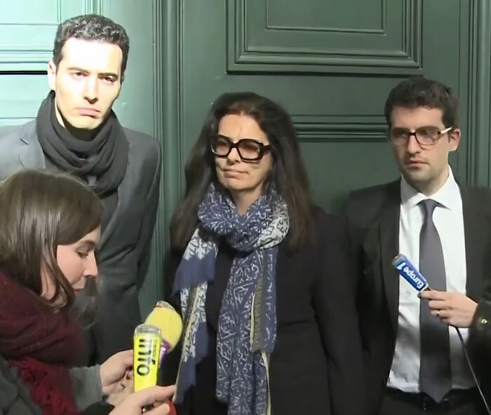 Three people in formal attire and scarves being interviewed by reporters with microphones on a city street about wealth disparities.