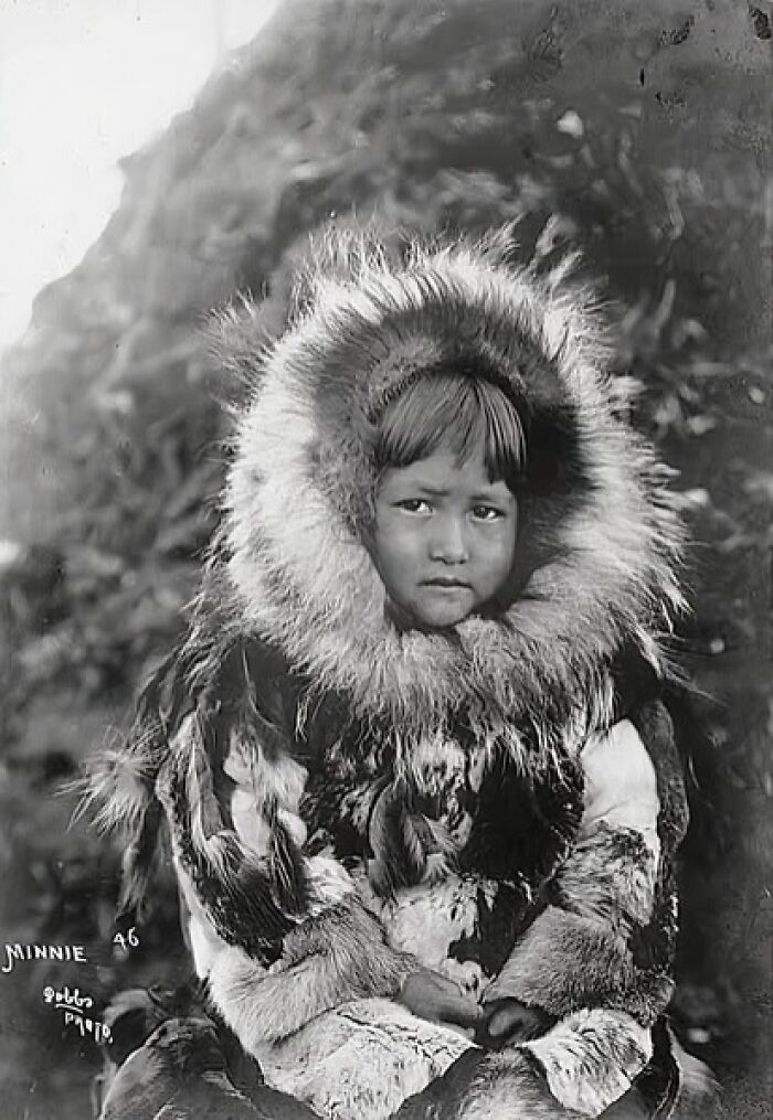 Young Inuit child wearing traditional fur parka, captured in a historic photo showing the unbreakable spirit of the Inuit.