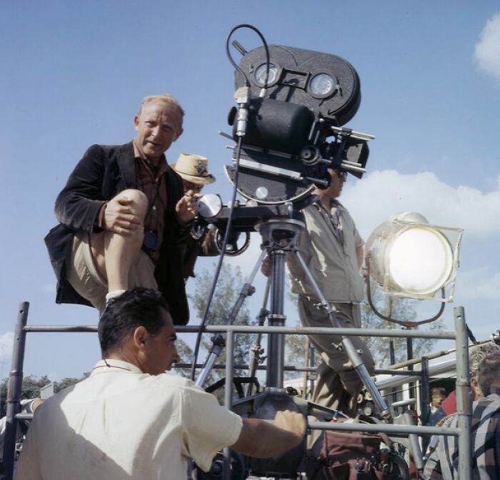 1950s Florida film crew operating vintage movie camera and lighting equipment during everyday life scene outdoors.