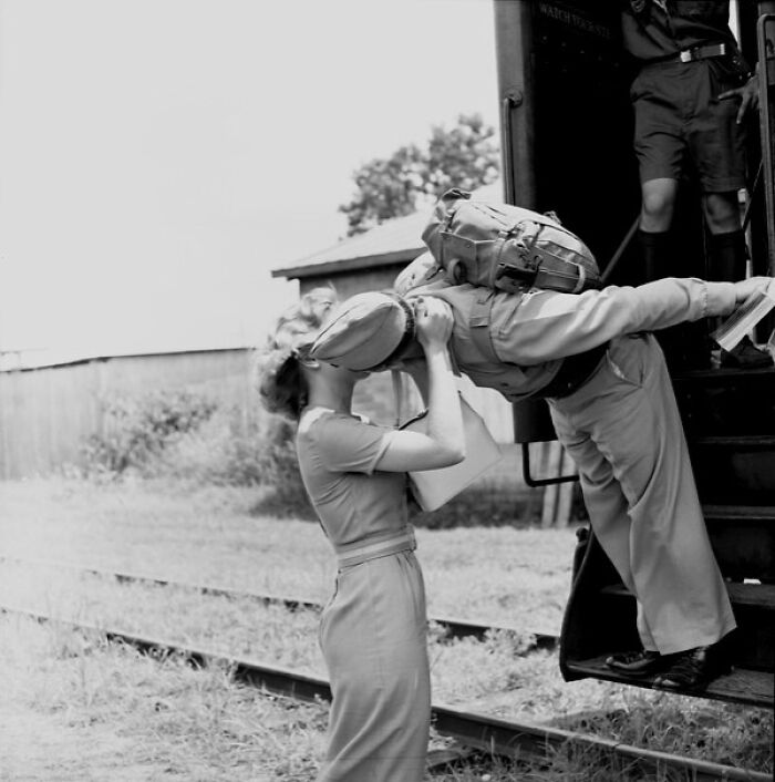Woman kissing soldier saying goodbye at train station, a nostalgic glimpse into everyday life in 1950s Florida.