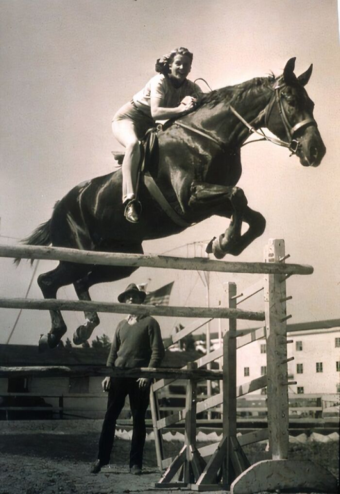 Woman riding horse jumping over fence, showcasing everyday life in 1950s Florida with equestrian activity.