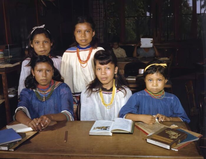 Five young students in traditional clothing sitting at a desk with books, capturing everyday life in 1950s Florida.