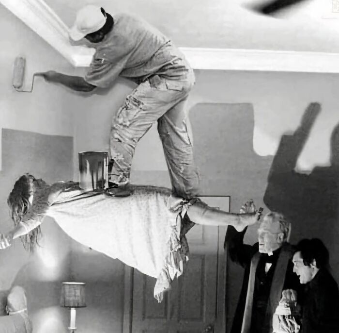 Man painting walls while standing on a woman levitating horizontally, creating one of the most cursed images online.