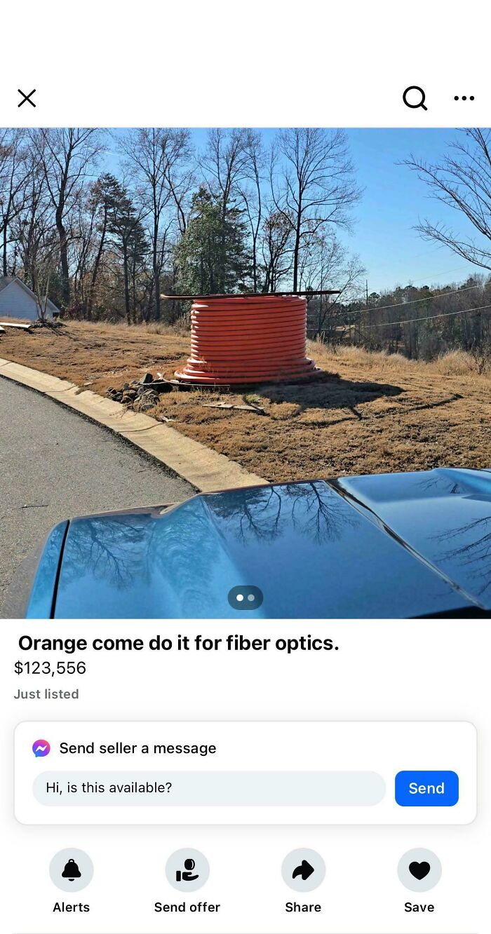 Large orange cable spool on roadside advertising fiber optics with a humorous typo questioning intelligence.