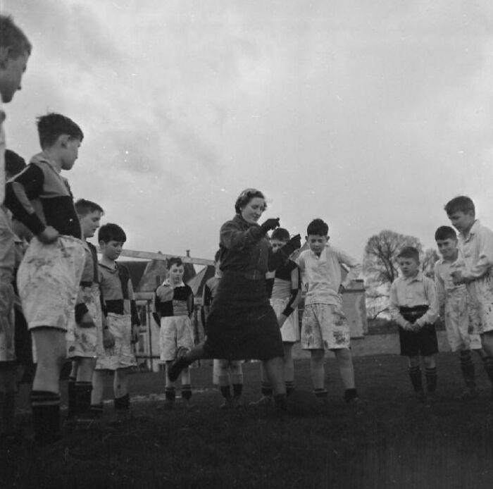 Teacher leading a group of schoolchildren in outdoor activities at a school worldwide during World War II.