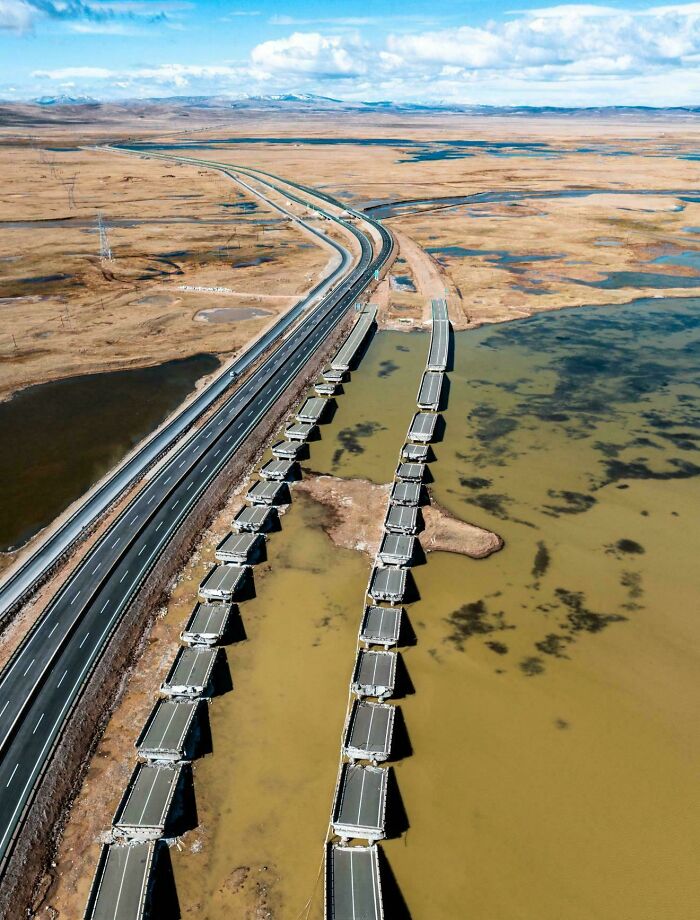 Aerial view of brilliant infrastructure with partially constructed bridge alongside a highway over a body of water.
