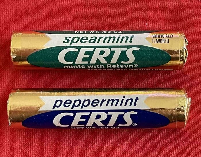 Two vintage Certs mint rolls, spearmint and peppermint flavors, displayed on a red background in nostalgic pics.