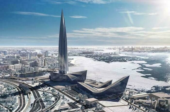 Futuristic evil building with sharp angles and a towering spire near icy waterfront, resembling structures from horror movies.