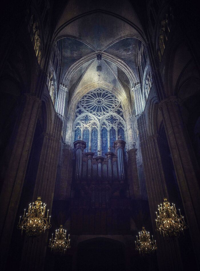 Gothic cathedral interior with eerie lighting and ornate chandeliers, showcasing sinister architectural details in a spooky setting.