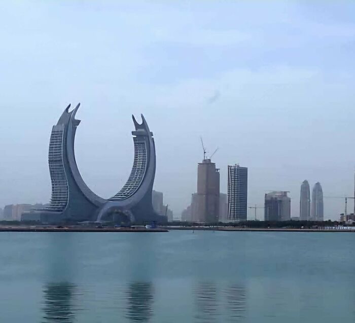 Futuristic evil buildings with curved towers by the water, resembling structures from a horror movie skyline.