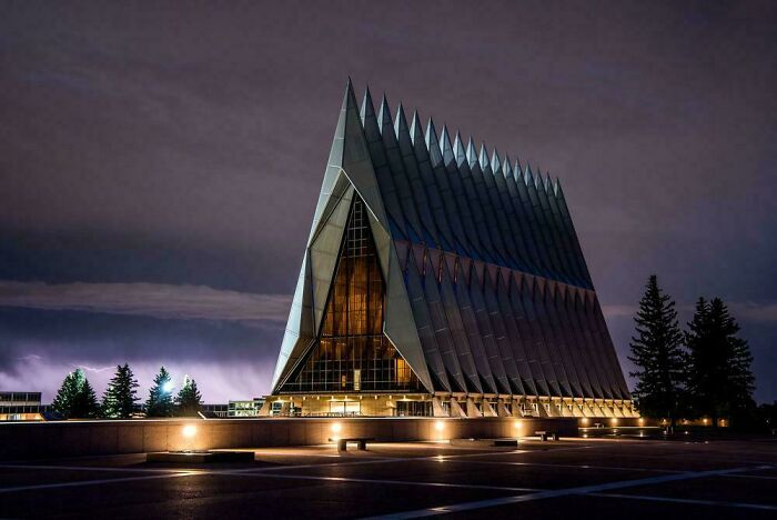 Evil building at night with sharp triangular features and illuminated windows against a dark cloudy sky.
