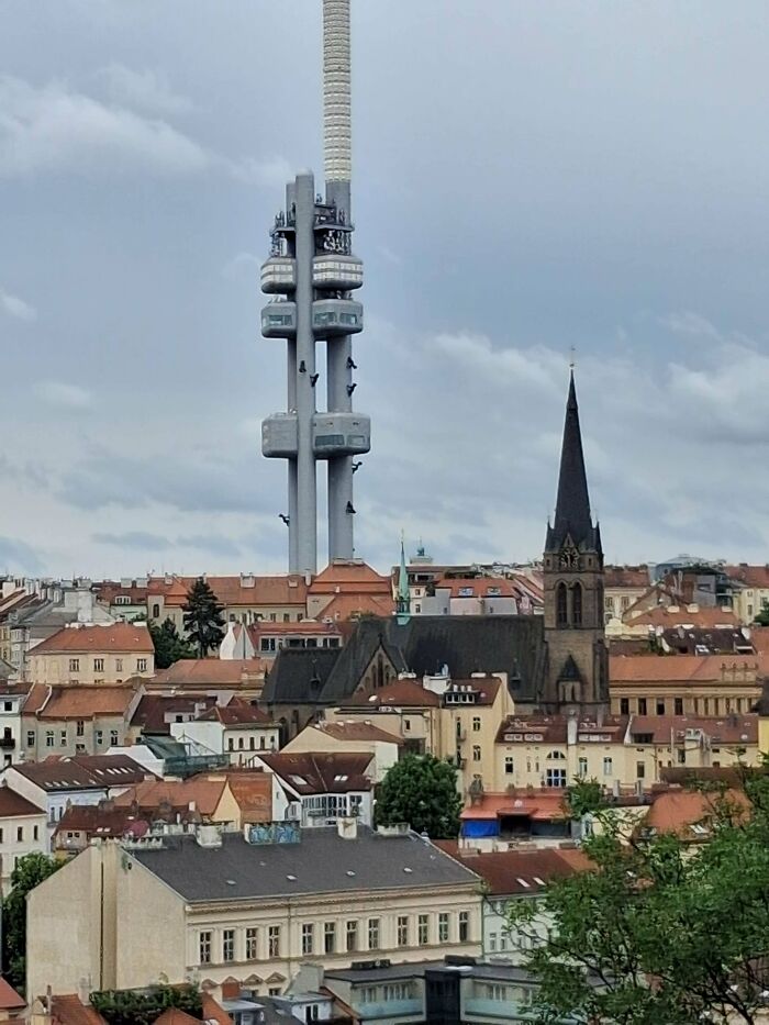 Tall futuristic tower with observation decks rising above a European cityscape, resembling evil buildings from horror movies.