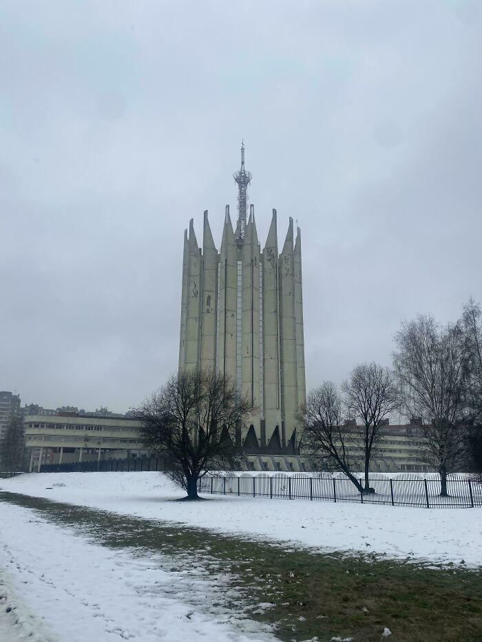 Tall eerie building with pointed spires in a snowy landscape, resembling evil buildings from horror movies.