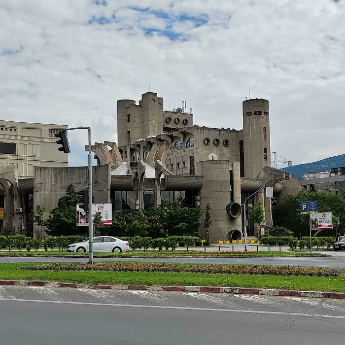 Brutalist concrete building with cylindrical towers and unusual shapes, resembling evil buildings from horror movies.