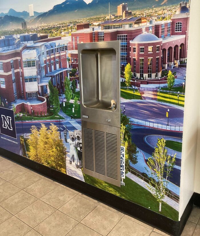 Drinking fountain mounted on a wall mural of a campus scene, illustrating funny advertising fails with unattainable body portrayals.