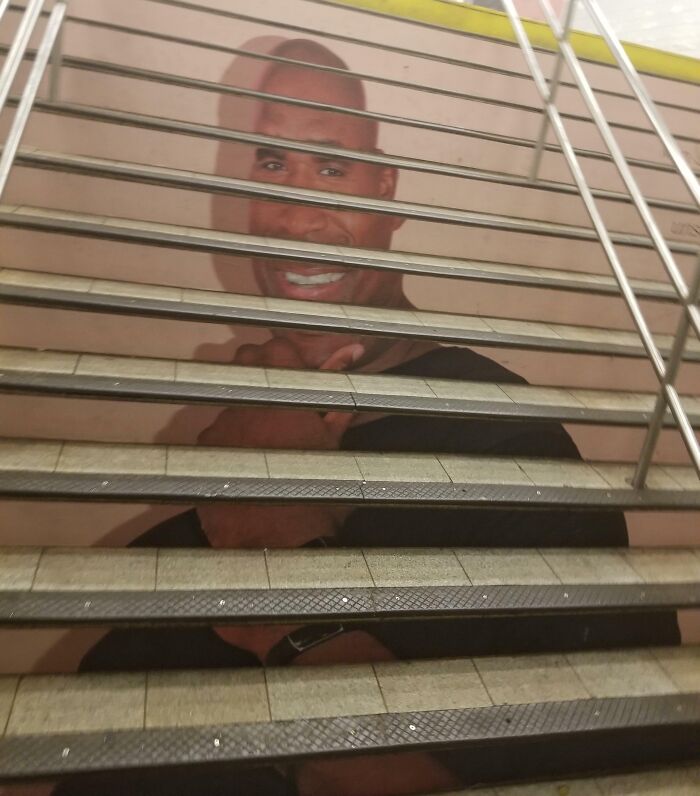 Staircase advertisement with distorted image of a smiling man, highlighting funny advertising fails and unattainable body portrayal.
