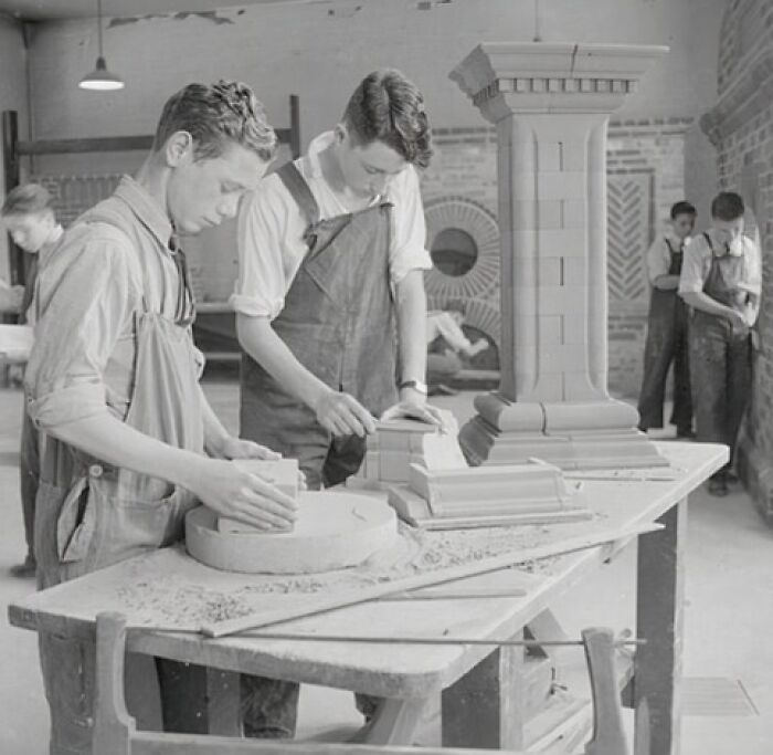 Boys in a World War II era school workshop crafting architectural models with brick and plaster materials.