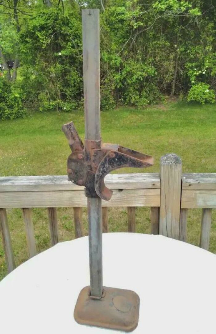 Rusty vintage car jack on a white table outdoors, evoking nostalgic feelings and memories of old age.