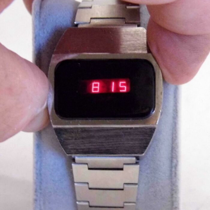 Vintage digital watch with red LED display held by fingers, evoking nostalgia and old age memories.