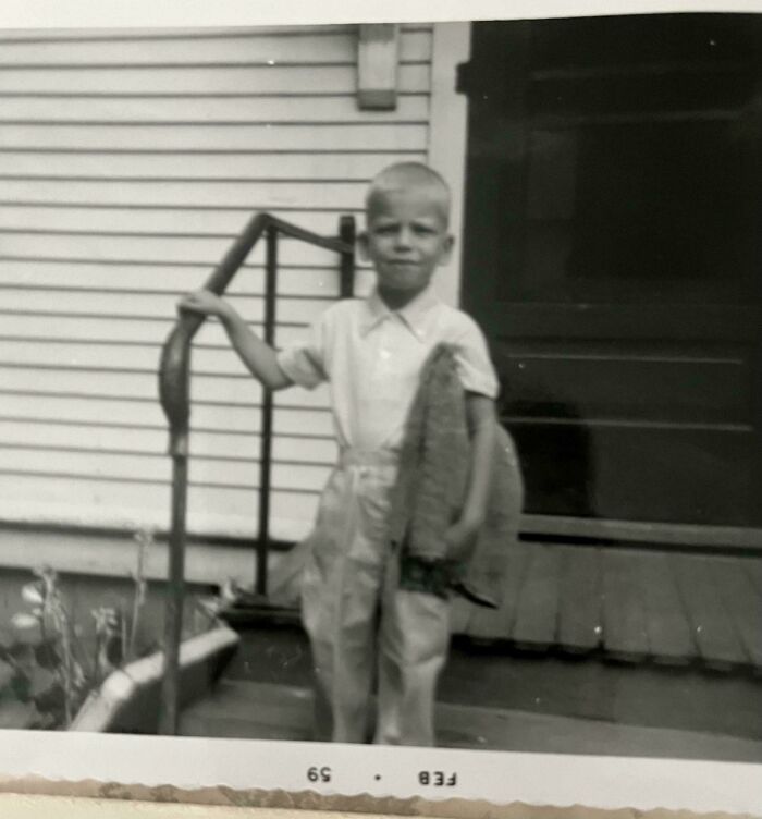 Black and white nostalgic photo of a young boy holding a large fish, evoking memories of old age and childhood.