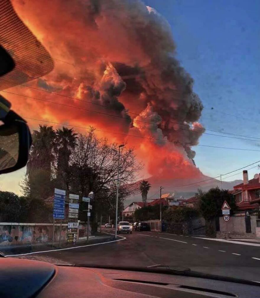 Volcanic eruption with massive smoke cloud glowing red over a suburban street, showcasing scary moments in nature.