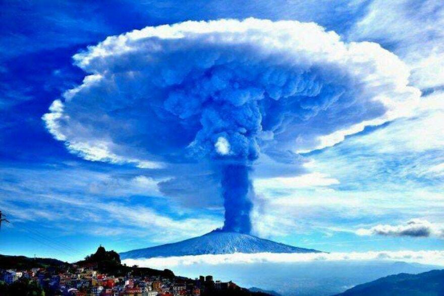 Volcano erupting with dramatic ash cloud spreading over sky, showcasing powerful and scary natural phenomenon.