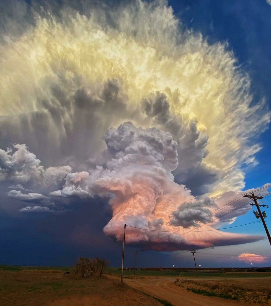 Massive swirling storm cloud formation over rural landscape showing scary nature phenomenon at dusk.
