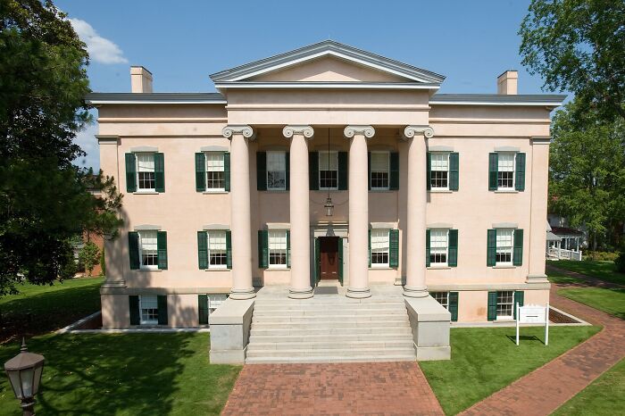 Historic home with classical columns and green shutters, representing America’s architectural heritage.