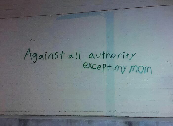 Graffiti on a wall reading against all authority except my mom, showing an awkward and humorous message.