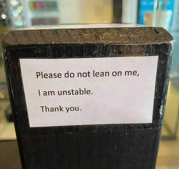 Sign on an unstable surface reads please do not lean on me in an awkward photo that is almost too painful to look at