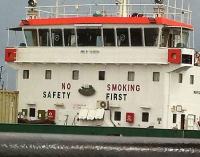 Ship exterior with awkward safety sign reading no safety smoking first, illustrating awkward photos that are almost painful to look at.